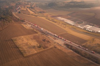 Aerial view of emergency vehicles on country road with visible tunnel and extensive fields at dusk,