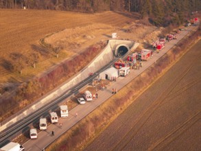 Fire engines and rescue workers in front of a tunnel in a rural area at sunset, fire drill on the