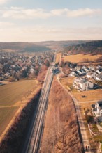 Aerial view of a village with railroad tracks surrounded by fields and hills, fire drill on the