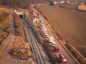 Aerial view of emergency vehicles and firefighters at a railway tunnel in an autumn landscape, fire