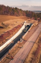 Train leaves a railway tunnel surrounded by emergency services and surrounding countryside, fire
