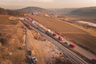 Fire trucks on a country road next to railroad tracks at sunset in a hilly landscape, fire drill on