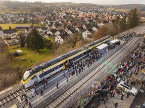 Arrival of the train, greeted by people, in a small village surrounded by nature, opening of the