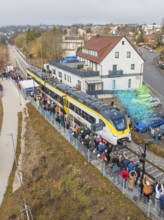 Regional train at a station event with crowds and rain of confetti in a city environment, opening