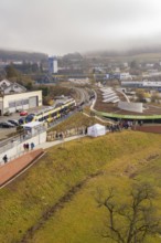 A large crowd gathers at a station area in a hilly landscape, opening of the Hermann Hesse Railway,