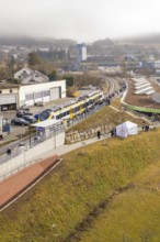 Landscape view with train and people along a railway line in an urban environment, opening of the