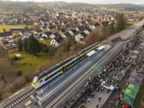 A train on a platform in a village, surrounded by a large crowd, opening of the Hermann Hesse