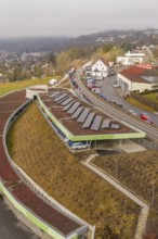 Solar panels on a hill in an urban landscape with cars and houses, opening of the Hermann Hesse