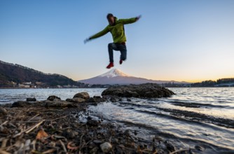 Young man jumping, Lake Kawaguchi, view of Mount Fuji volcano at sunset, Yamanashi Prefecture,