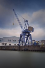 View of a crane standing directly at a harbor basin, Bremerhaven, Bremen, Germany