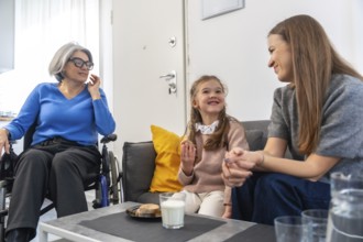 Loving three generation familygrandmother in wheelchair, mother and young daughter sharing smiles,