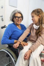 Granddaughter tenderly interacting with her smiling grandmother in a wheelchair, symbolizing strong