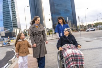 Family members and a caregiver pushing an elderly woman in a wheelchair, leaving a healthcare