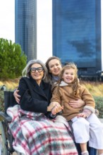 Three generations of women, grandmother in wheelchair covered with a blanket, daughter and
