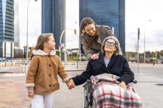 Three generations of women, including a senior woman in a wheelchair, a smiling adult daughter