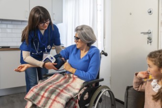 Healthcare professional assisting an elderly woman in a wheelchair by measuring her blood pressure
