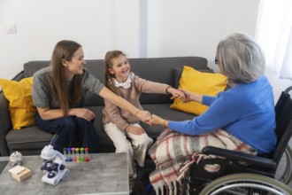 Three generations of women, a cheerful child, her mother, and a senior grandmother in a wheelchair,