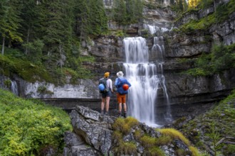Young pretty hiker standing on rocks in front of Cascata di Mezzo waterfall, long exposure,