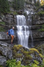 Hiker standing in front of Cascata di Mezzo waterfall, long exposure, Vallesinella, Brenta,