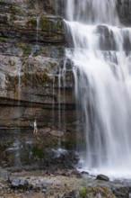 Little hiker in front of large Cascata di Mezzo waterfall, long exposure, Vallesinella, Brenta,