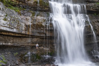 Little hiker in front of large Cascata di Mezzo waterfall, long exposure, Vallesinella, Brenta,
