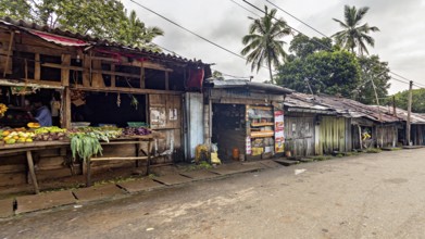 Abandoned street market area with wooden huts and tropical palm trees, small shops on the side of a