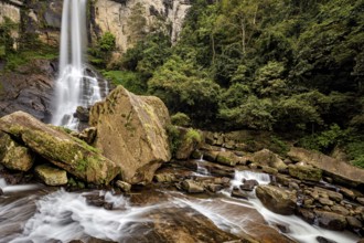 A large waterfall in the jungle surrounded by massive rocks and lush greenery, waterfall in the