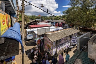 View of a depot densely staffed by buses, surrounded by billboards and trees, Kandy bus station in