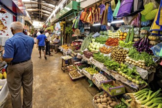 Market stall with a plethora of fresh vegetables and people shopping, The old market halls of Kandy
