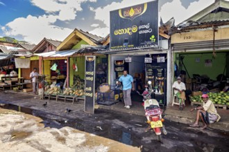 Rural street scene with small shops and people standing on the side of the road, The old market