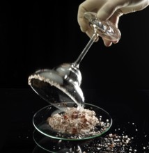 The glass rim of a margarita bowl is prepared with a salt and spice mix for the cocktail, studio