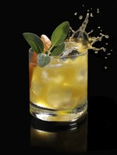 An ice cube cube falls into a tumbler and allows the liquid to splash on, studio shot against a