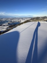 Shades of a ski tourer on fresh snow, view of Forggensee and Bannwaldsee with snow in winter, ski