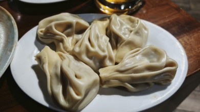 Delicious stuffed dumplings, Georgian cuisine, khinkali on a white plate, served on a wooden table,