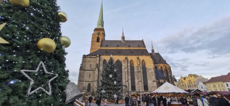 Christmas market in front of a big church with festive decoration and people, Pilsen, Czech