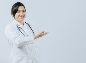 Young asian doctor presenting something isolated. Smiling asian female doctor showing empty space