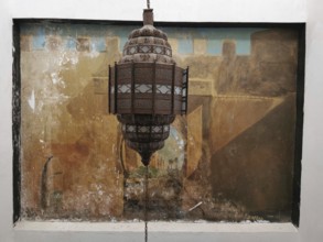 Traditional Moroccan lantern in front of a mural in warm tones, Morocco