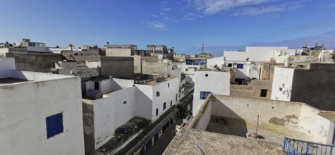 View over the rooftops of an old town with white buildings and blue sky, southern Morocco