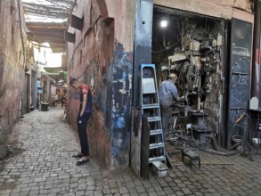 A man leaning against a wall in front of a chaotic workshop in the Medina, atmospheric picture,