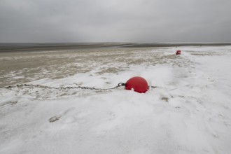 Red buoy on snowy beach, Langeoog, Lower Saxony, Germany