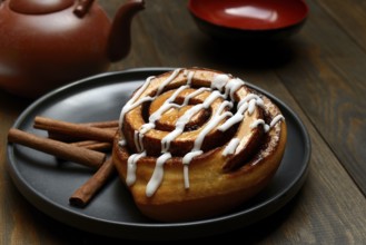 Cinnamon roll on plate and cinnamon sticks