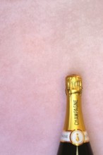 Champagne bottle on pink background, New Year's Eve