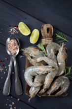 Fresh raw, white-footed shrimp, tiger prawns vannamei, on a wooden cutting board, with lime slices,