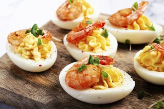 Boiled eggs stuffed with yolk and seasoned with mayonnaise, stuffed eggs with shrimp, on a wooden