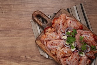 Chicken wings, marinated and laid out on a wooden platter, ready for cooking, grilling or baking,