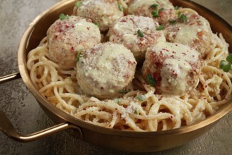 Spaghetti with chicken meatballs, with cream sauce, and parmesan cheese, and decorated with