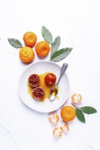 A plate with a spoonful of tangerine jam, fresh tangerines, on a marble table, top view