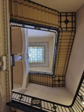 Historic staircase with artfully designed railing and glass window on the ceiling, Berlin, Germany