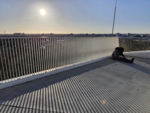 A person sitting alone on a railing with a view of an urban landscape at sunset, abstract, stripes,