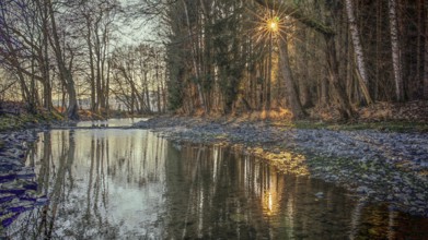 Romantic river landscape at sunset with rays of light through the trees and a peaceful atmosphere,